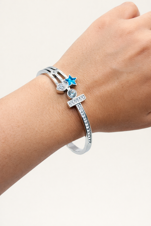 Silver bracelet with star-shaped charm on a wrist against a white background